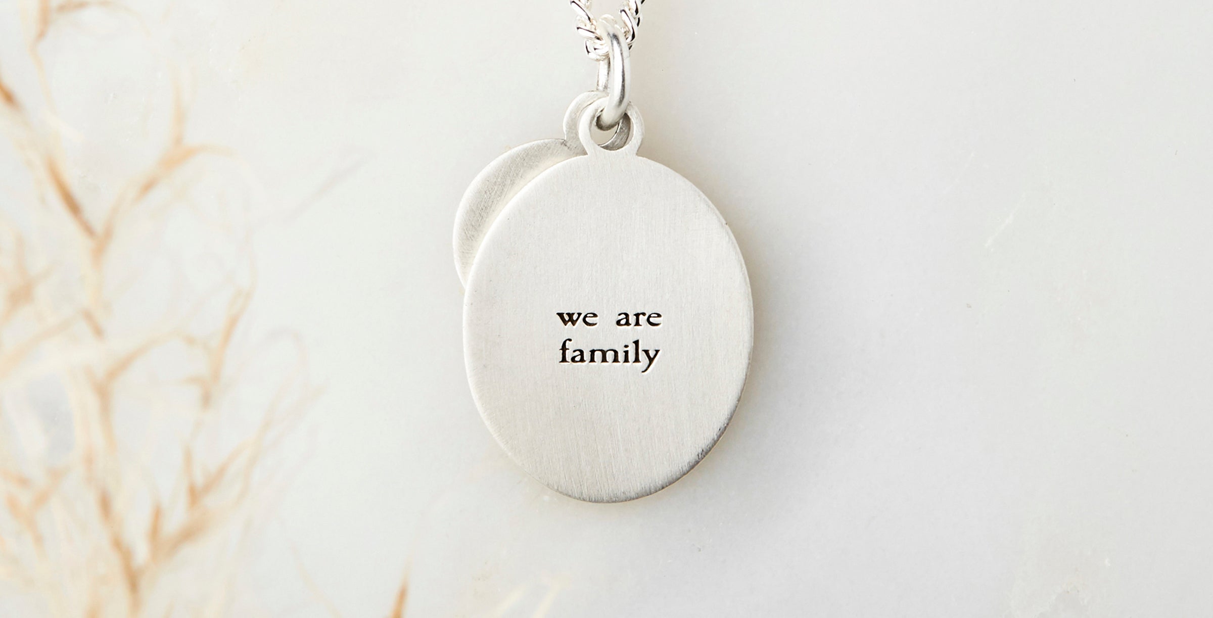 The back of a sterling silver oval pendant engraved with 'we are family'