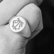 Black and white monogram signet ring on a finger