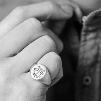 Black and white monogram signet ring on a finger